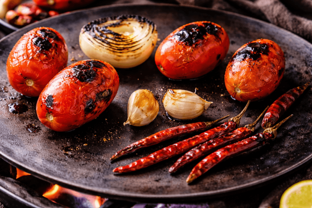 Tomatoes, chiles de árbol, garlic, and onion charring on a hot comal for salsa tatemada