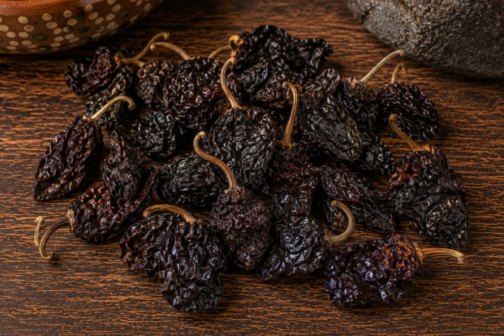 Dried morita chiles on a rustic wooden surface used in Mexican salsa recipes