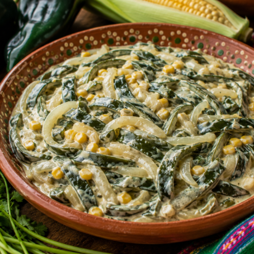 Rajas con crema with roasted poblano pepper strips, sliced onions, corn, and Mexican crema served in a traditional clay bowl.